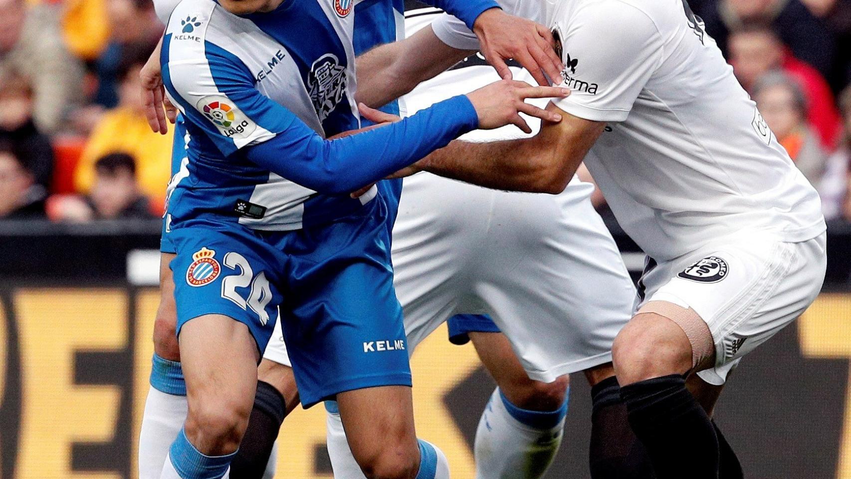 Wu Lei pugna con un jugador del Valencia en el partido de Liga entre ambos