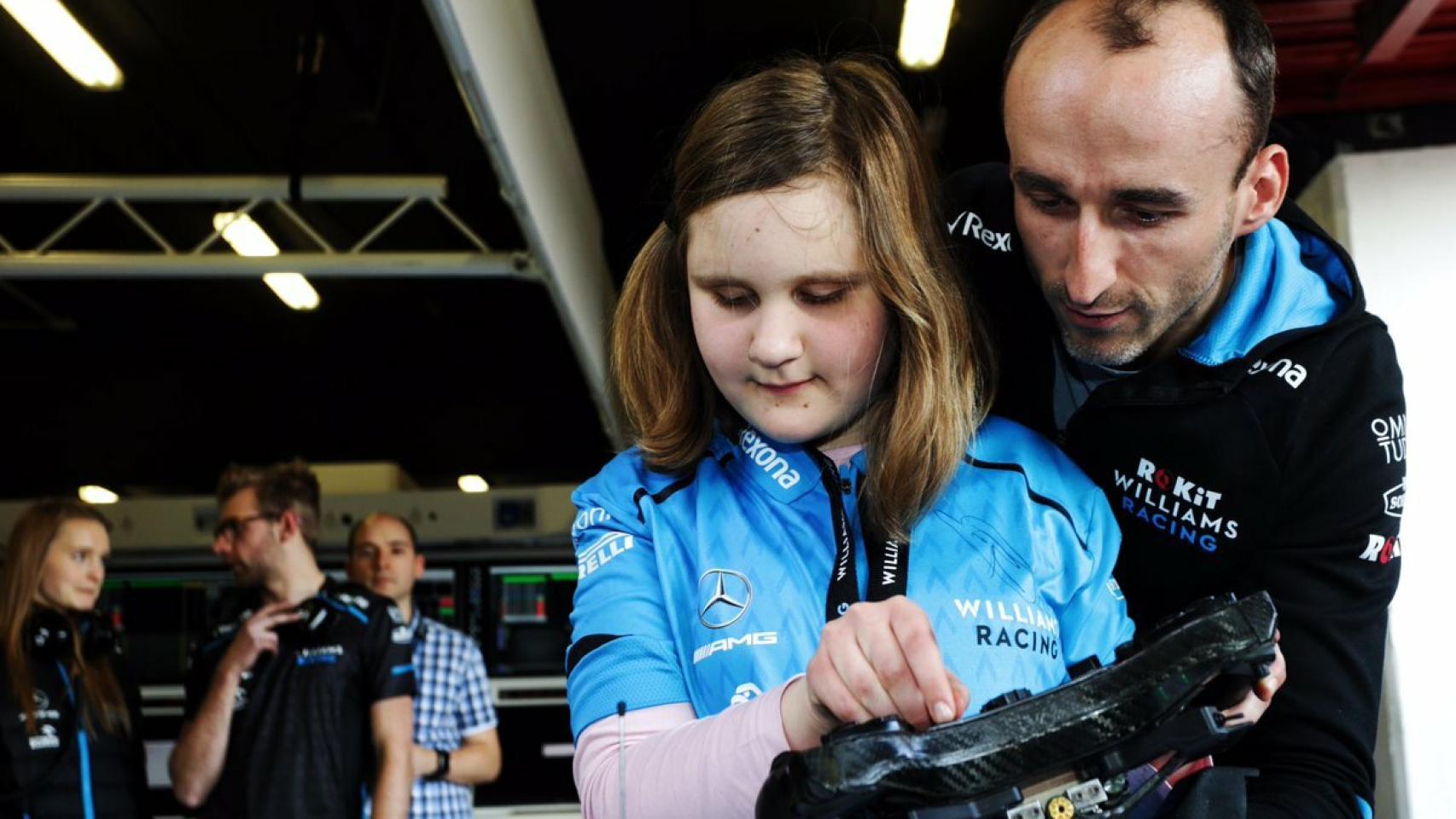 Kubica muestra mediante el tacto el coche a una niña ciega. Foto: Twitter. (@PKN_ORLEN)