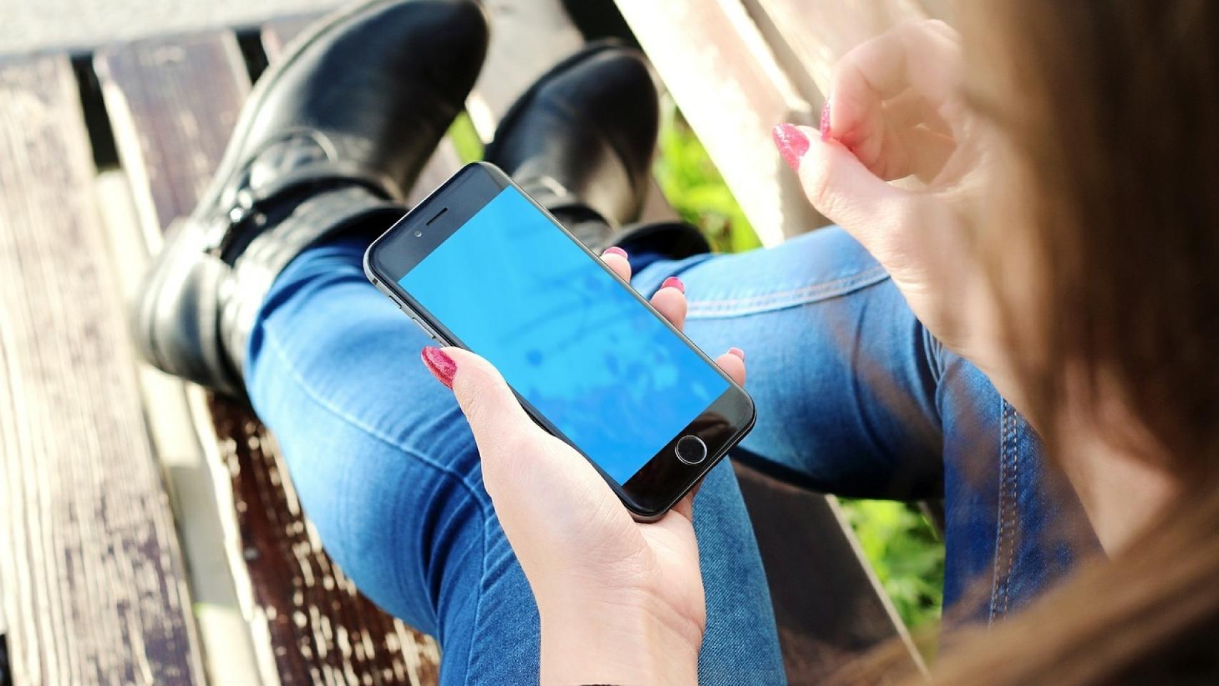 Una joven que consulta constantemente el teléfono móvil