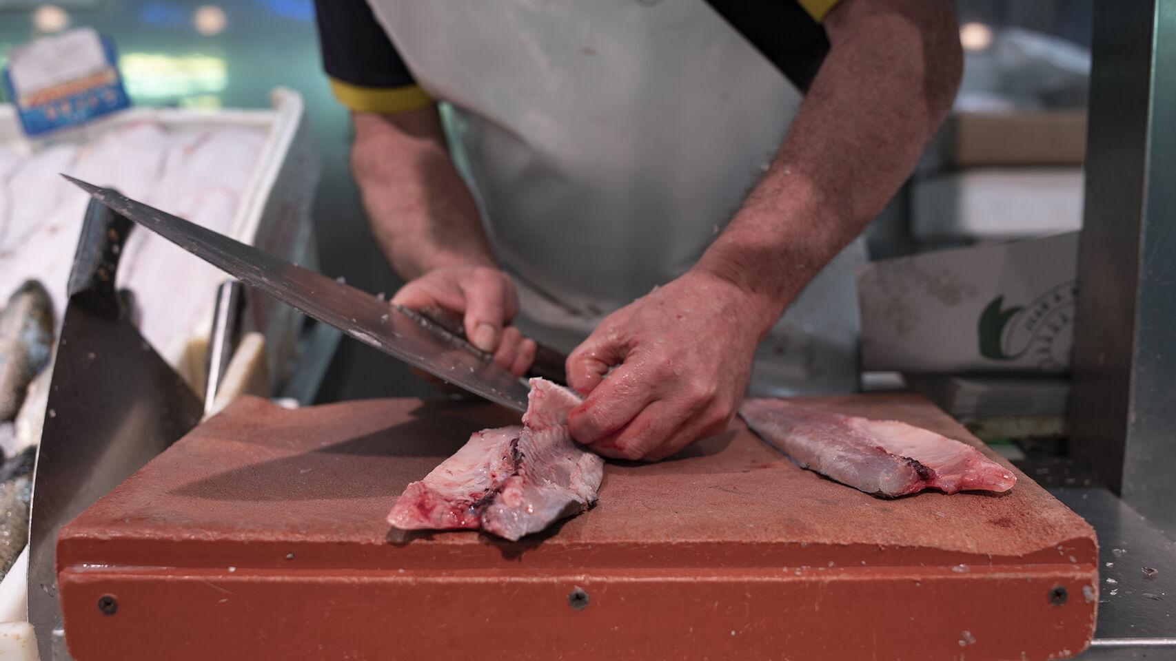 Un pescadero cortando un pez pescado recientemente