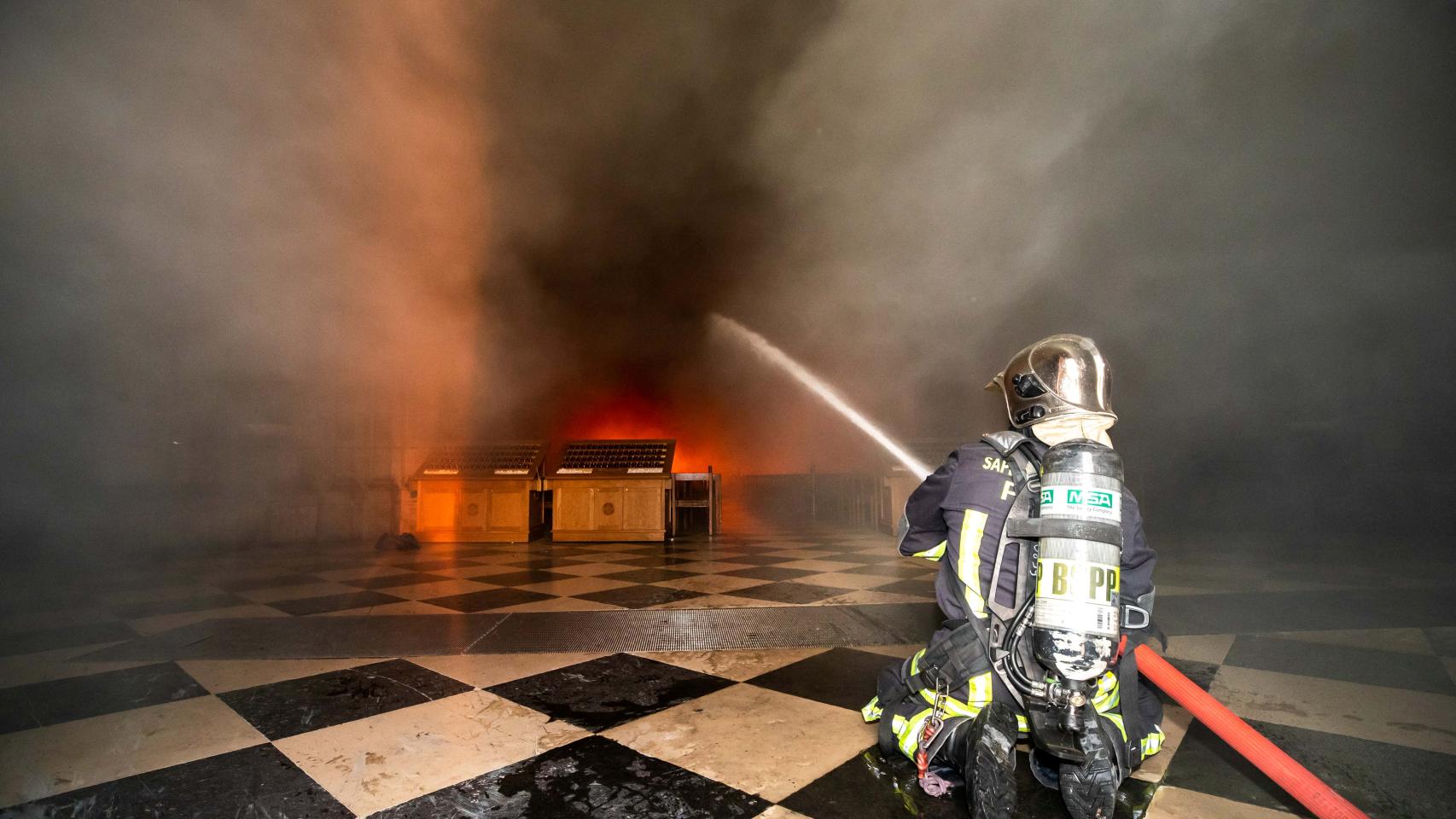 Un bombero intentando controlar las llamas en la catedral