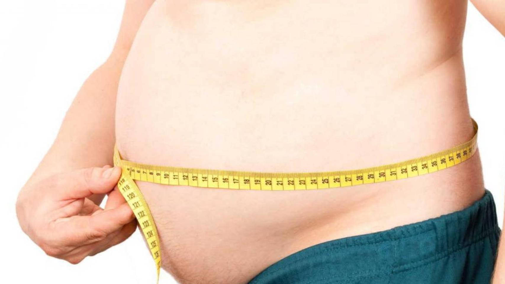 Un hombre midiéndose el perímetro abdominal.