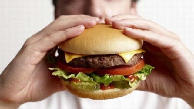 Un hombre se come una hamburguesa doble.