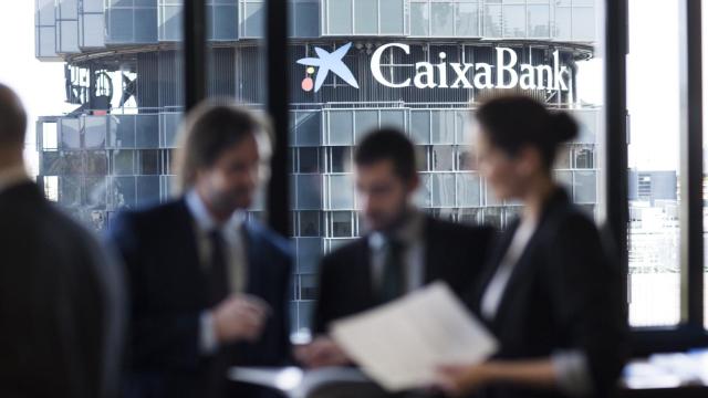 Una oficina de Caixabank con el logo detrás.