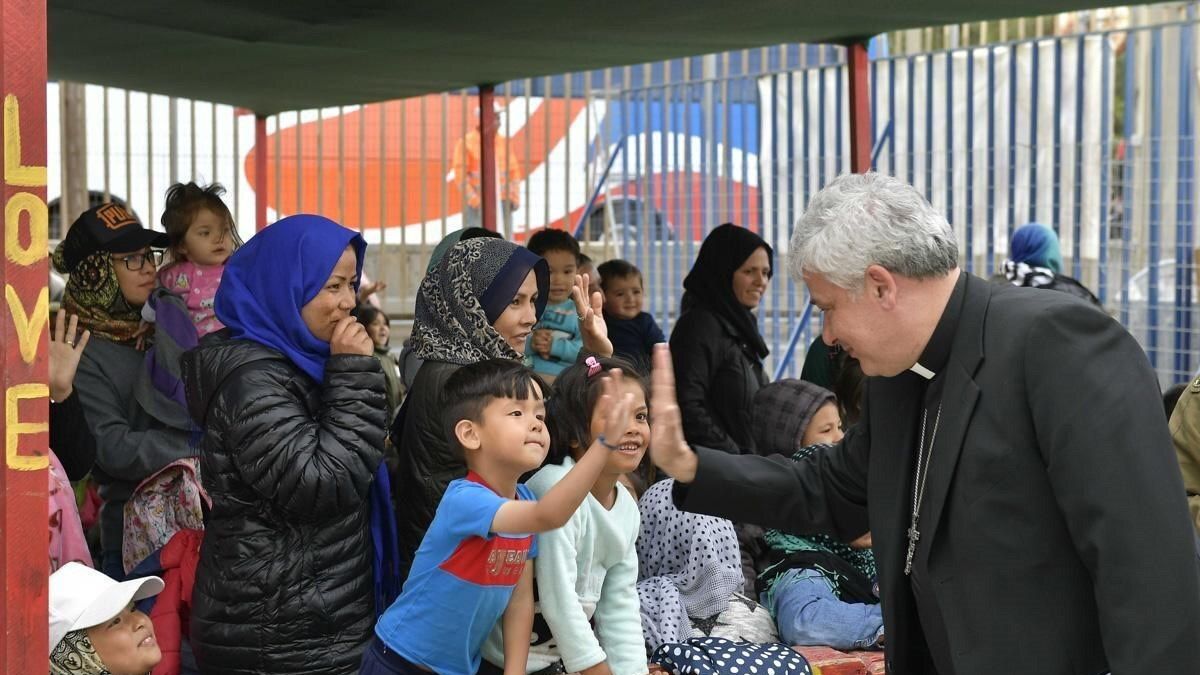 El limosnero del Papa, Konrad Krajewski, saluda a un niño en un campamento de refugiados en Grecia.