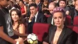 Rapinoe le entrega el balón firmado al niño sin mirarle