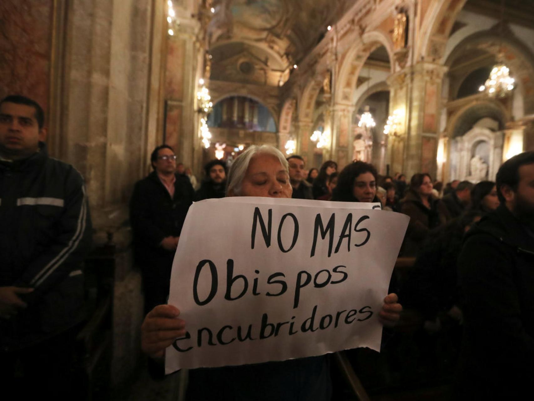Una manifestane sosteniendo un letrero durante una misa en Santiago de Chile.