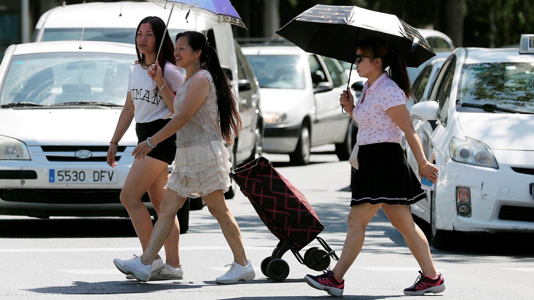 Tres mujeres se protegen del sol y del calor con sombrillas en Valencia. EFE/Kai Försterling