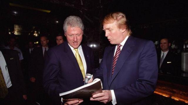 Trump le enseña un libro a Clinton en junio del año 2000.