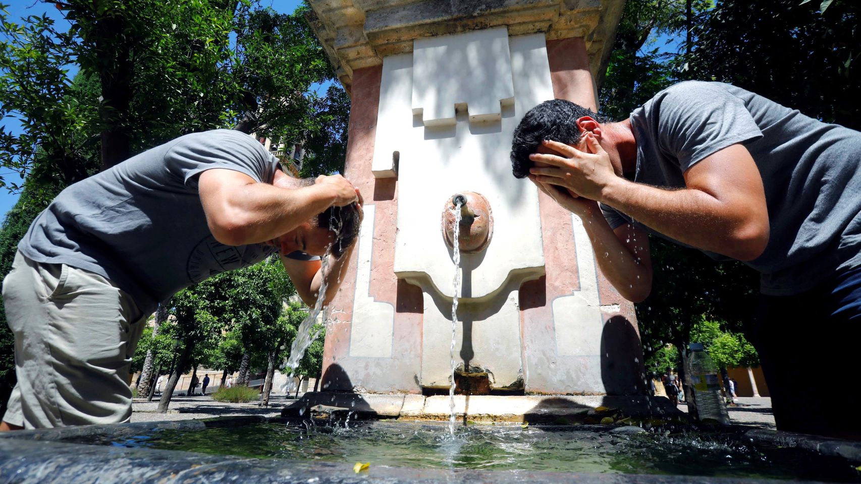 Unos turistas se refrescan en una fuente de Córdoba.
