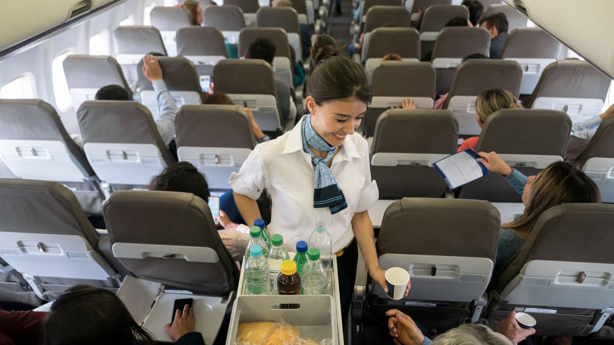 Una azafata atiende a los pasajeros de un avión.