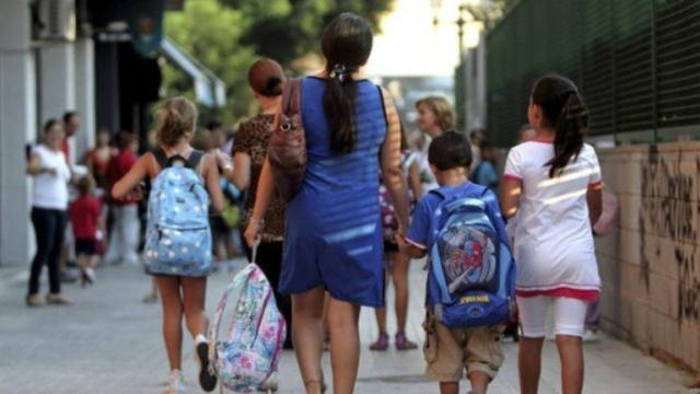 Varias madres con sus hijos en la entrada al colegio.
