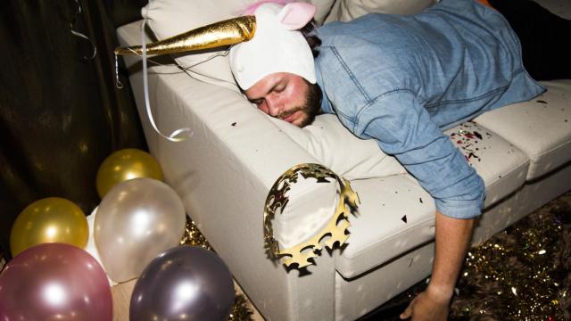 Un hombre descansa en un sofá tras una noche de consumo de alcohol.