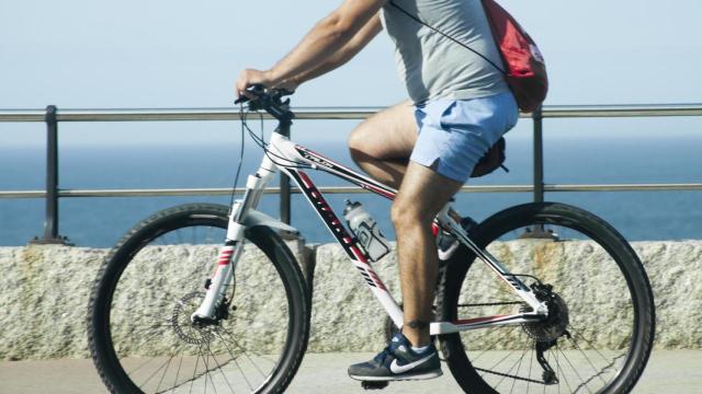 A Coruña, Galicia, Spain- September 9, 2016: Side view of young man cycling by the sea in La Coruña, Galicia, Spain.