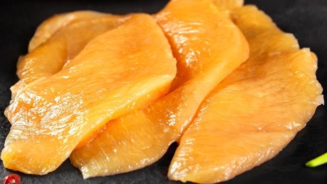 Unos filetes de pollo sobre un plato de pizarra negra.