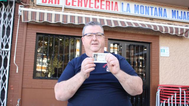 Daniel muestra su décimo de Lotería a las puertas de su bar.