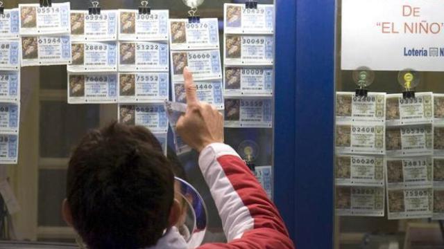 Un hombre escoge un número de la Lotería de Navidad en una administración