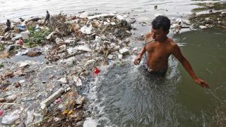 Un hombre se cepilla los dientes en el agua contaminada del río Ganges en Kolkata, India.