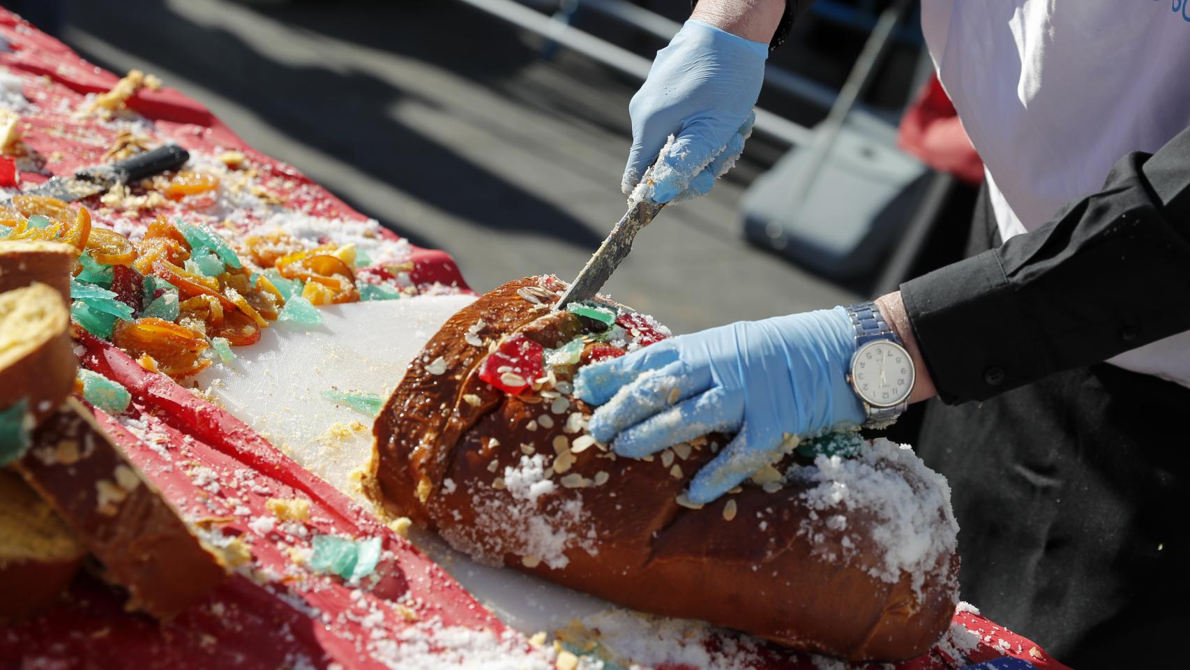Un hombre corta un roscón de Reyes en rebanadas.