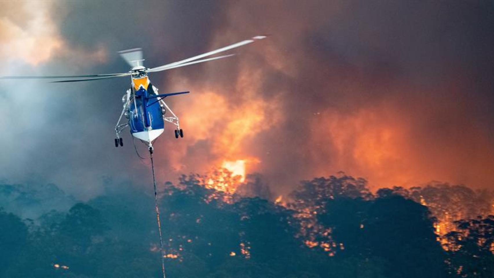 un helicóptero de extinción de incendios aborda un incendio cerca Gippsland del Este de Victoria, Australia.