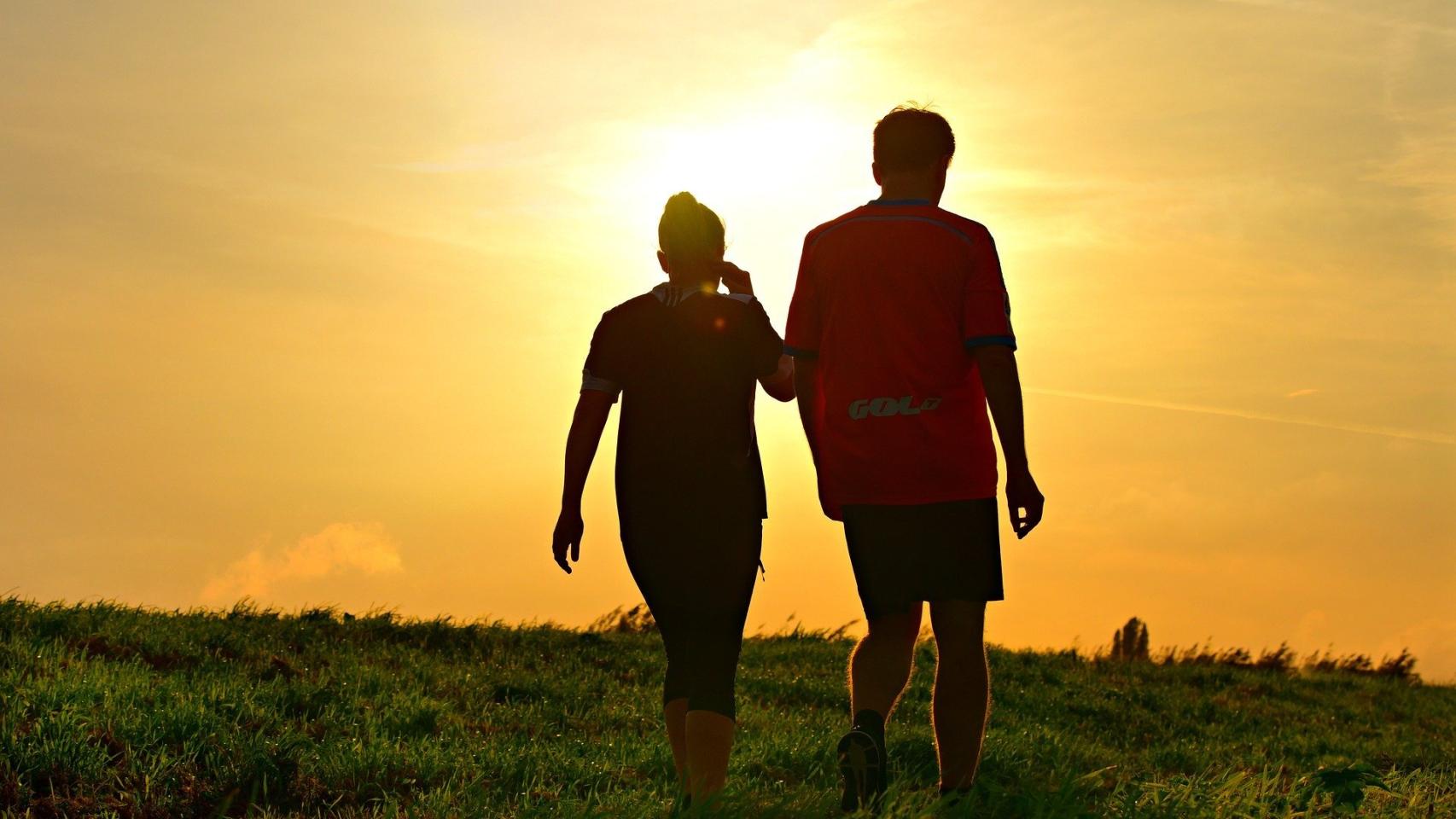 Dos personas caminando al atardecer.
