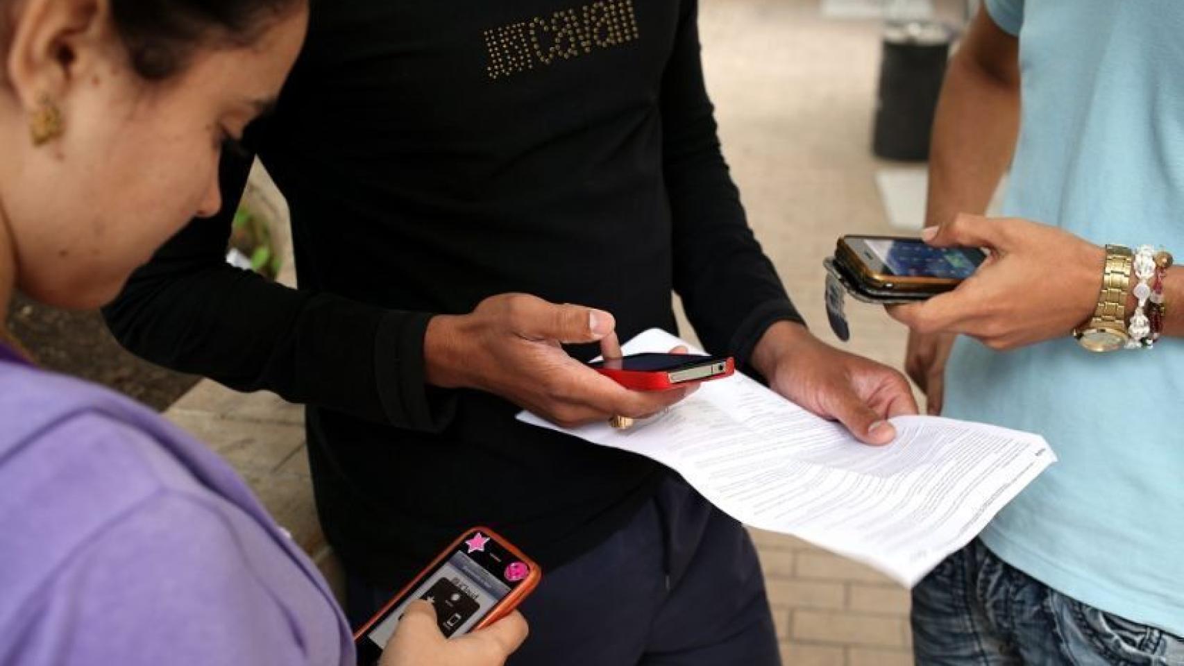 Tres jóvenes con móviles en la mano.