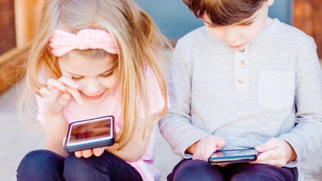 Niños jugando con teléfonos.