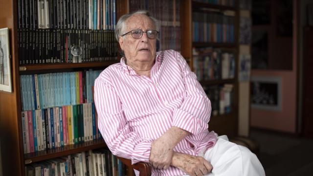 El escritor, en su despacho, junto a la colección total de sus 100 novelas.