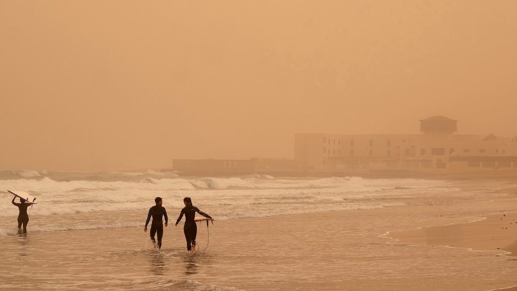 Surfistas en Puerto del Rosario (Fuerteventura) bajo la calima. EFE/Carlos de Saá.