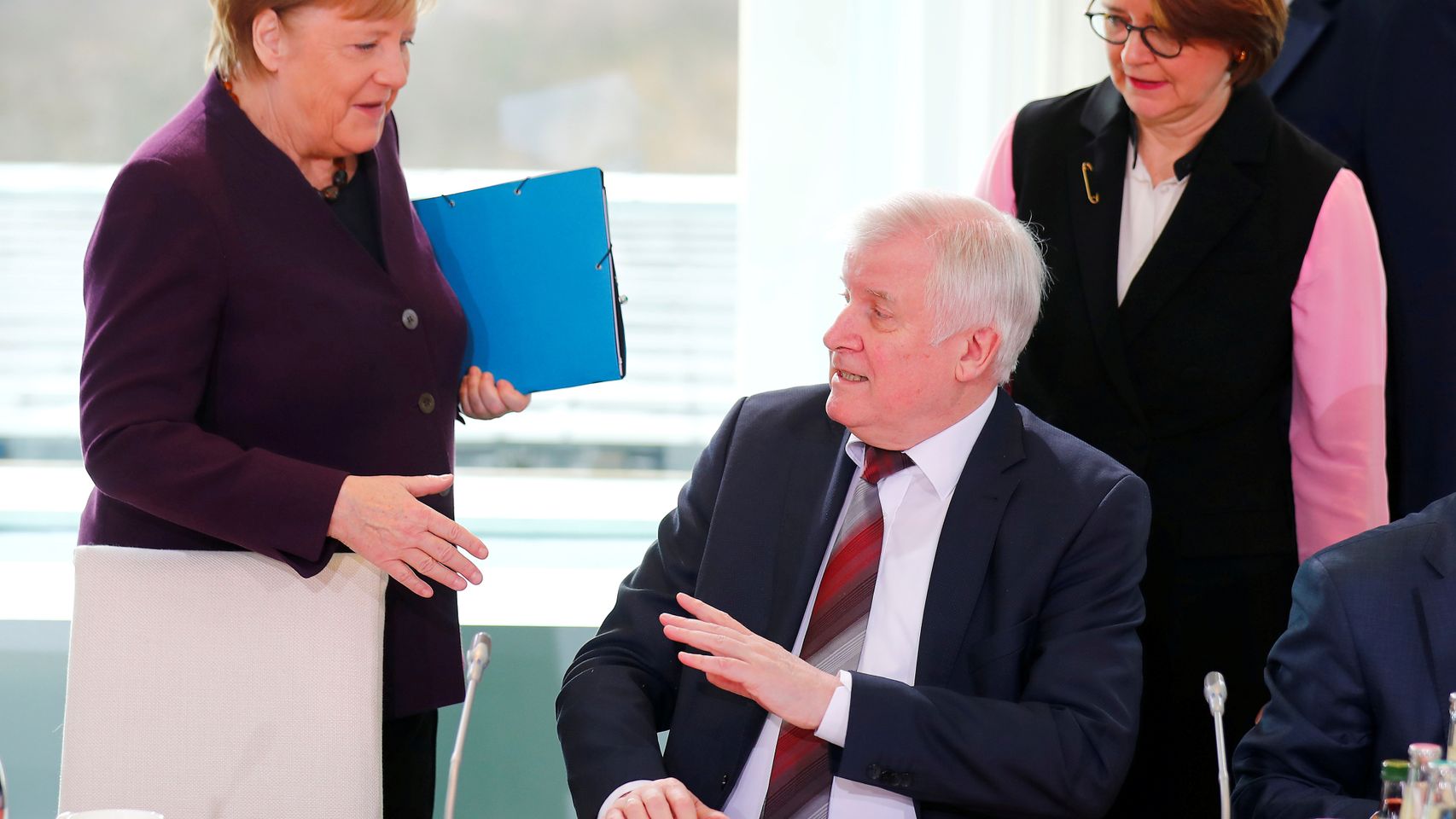 Angela Merkel intenta dar la mano al ministro de Interior, Horst Seehofer, que lo rechaza para evitar contagios.