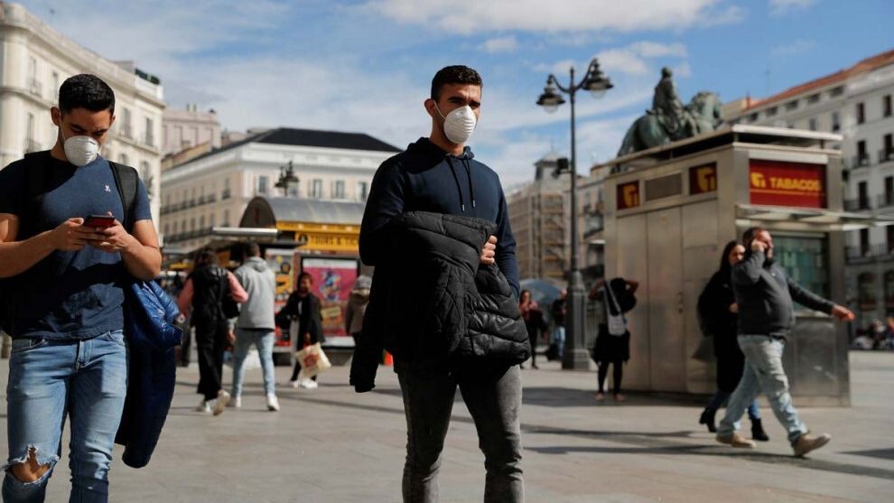 Dos jóvenes caminan con mascarilla por la Puerta del Sol de Madrid.