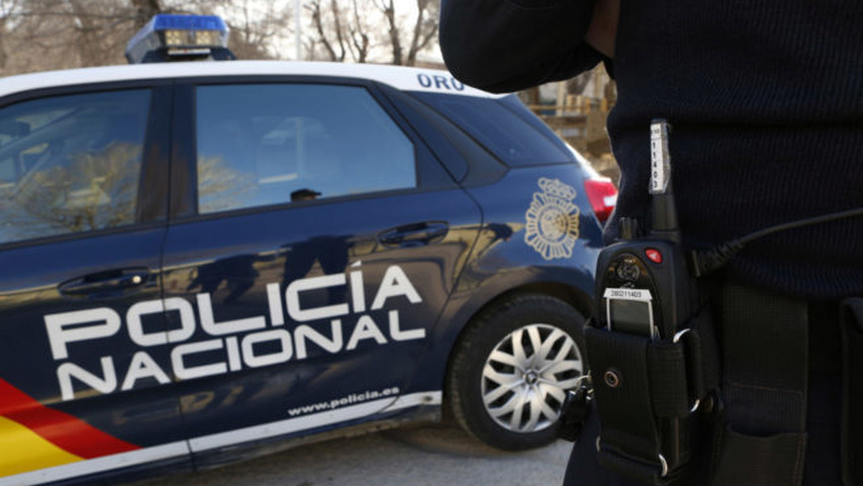 Un agente de la Policía Nacional junto a su vehículo.