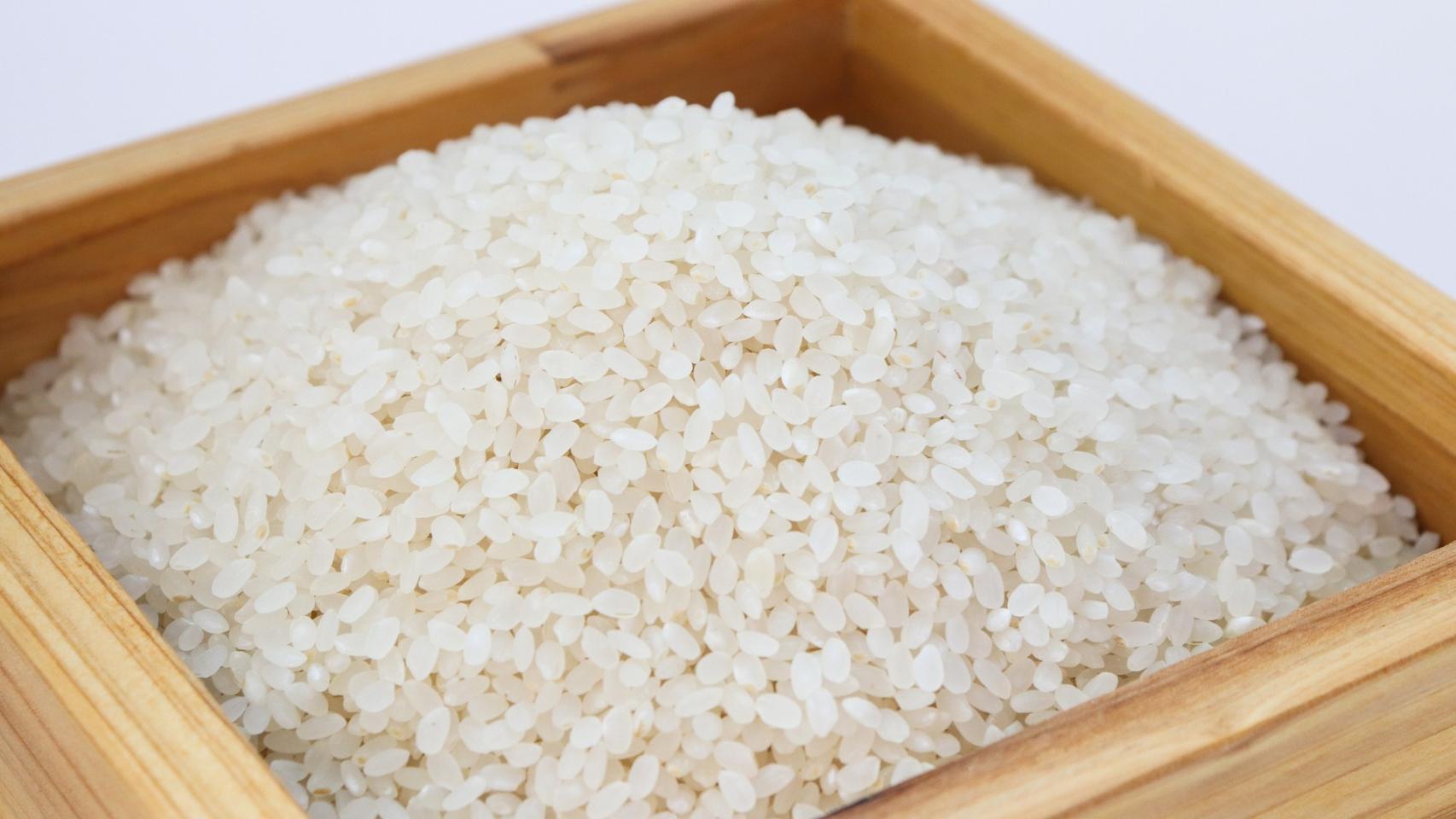 Una caja de madera repleta de arroz crudo.
