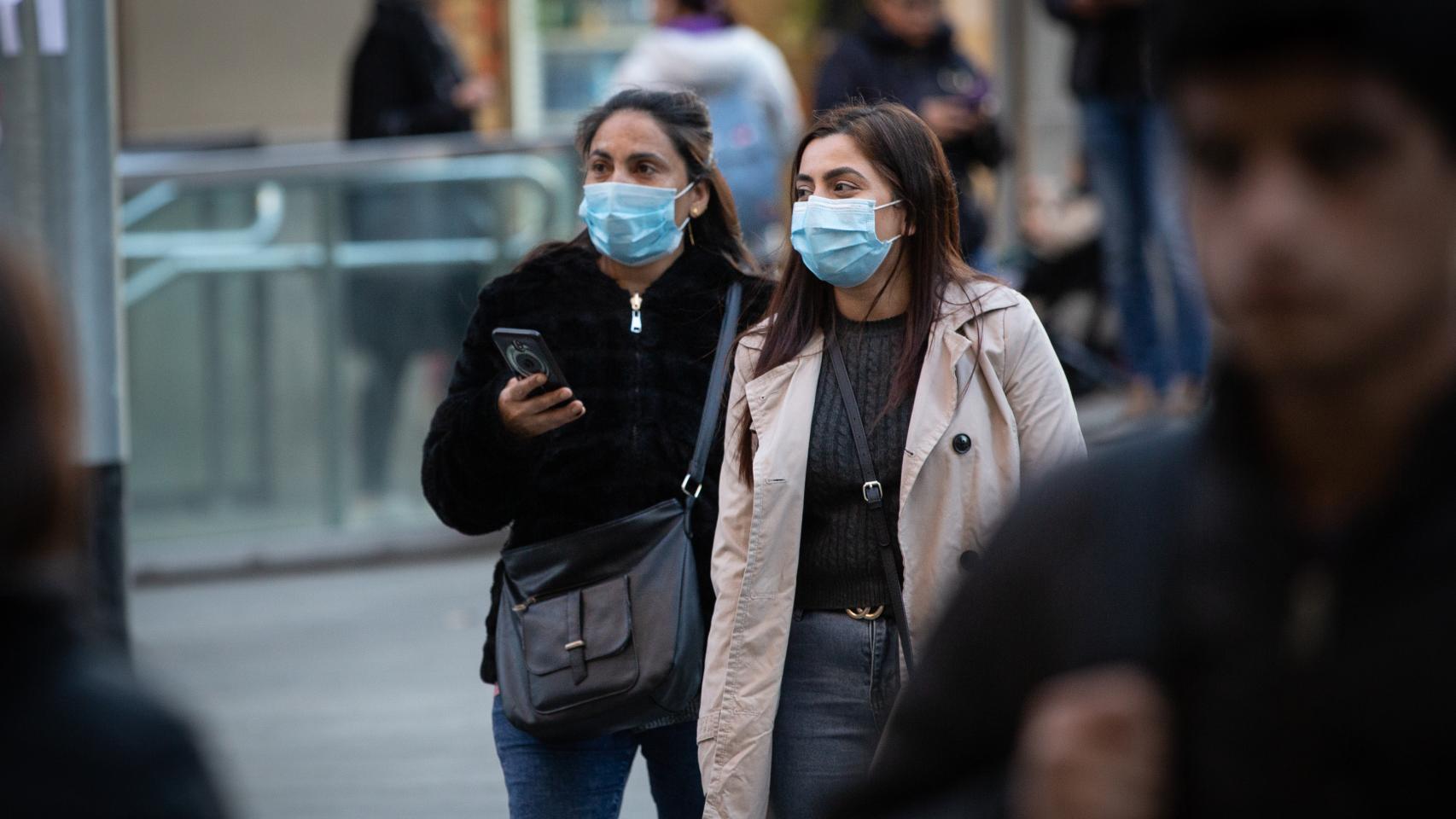 Dos jóvenes con mascarilla por las calles de Barcelona.
