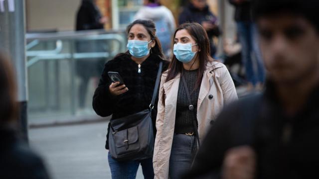 Dos jóvenes con mascarilla por las calles de Barcelona.