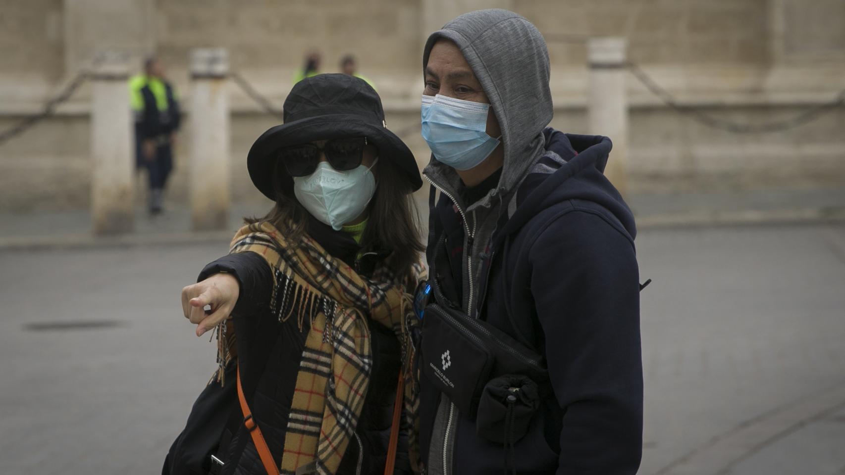 Dos turistas con mascarillas.