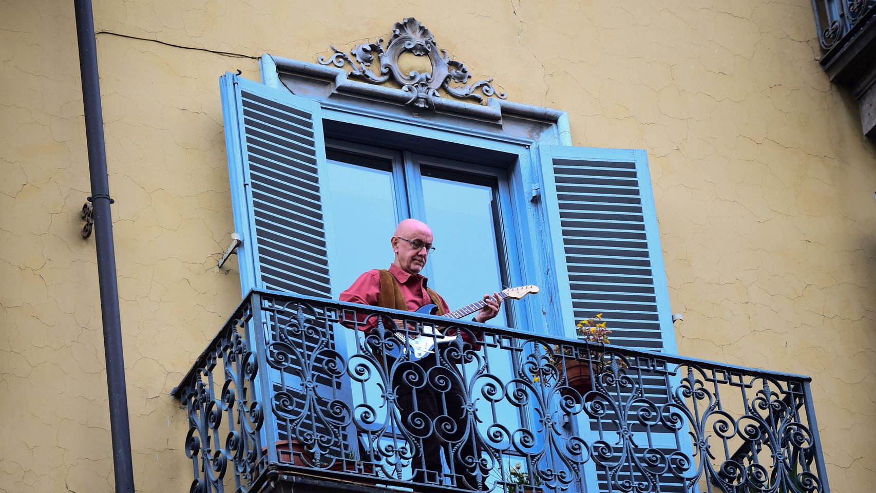 Un hombre toca la guitarra desde el balcón de su casa, en Turín.