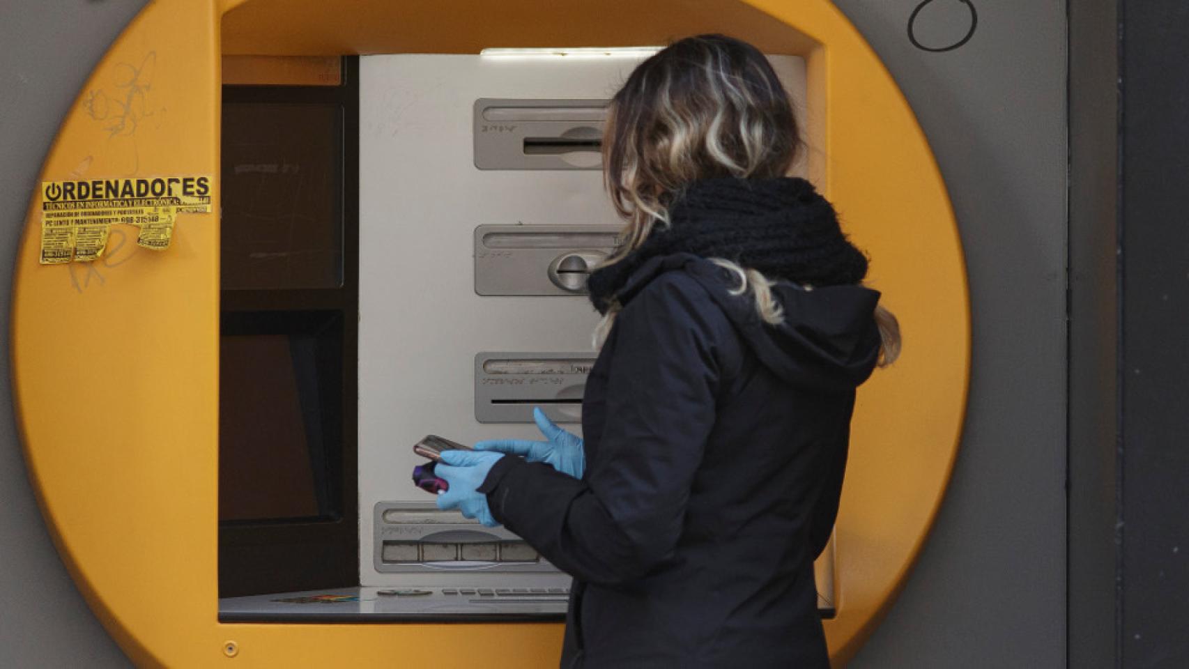 Mujer sacando dinero del cajero en imagen de archivo.