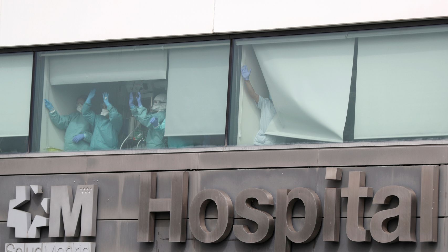 Sanitarios del hospital de La Paz de Madrid saludan desde las ventanas del centro médico.