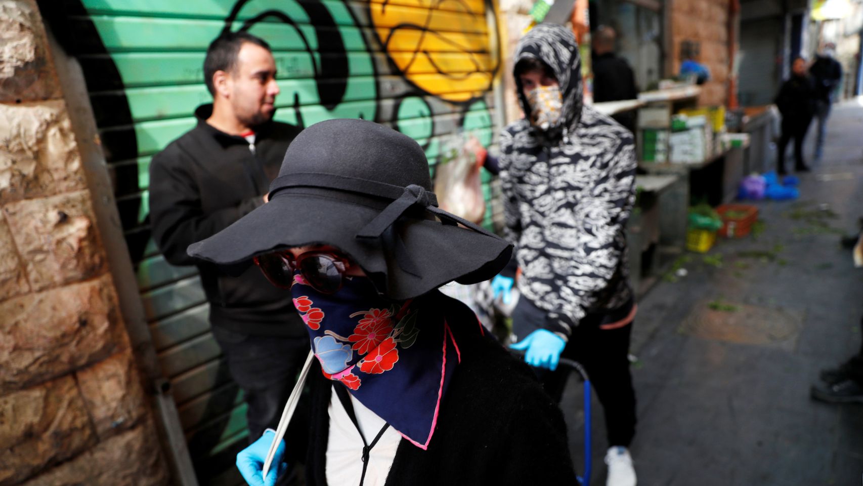 Una mujer ataviada con una mascarilla pasea por una calle de Jerusalén.