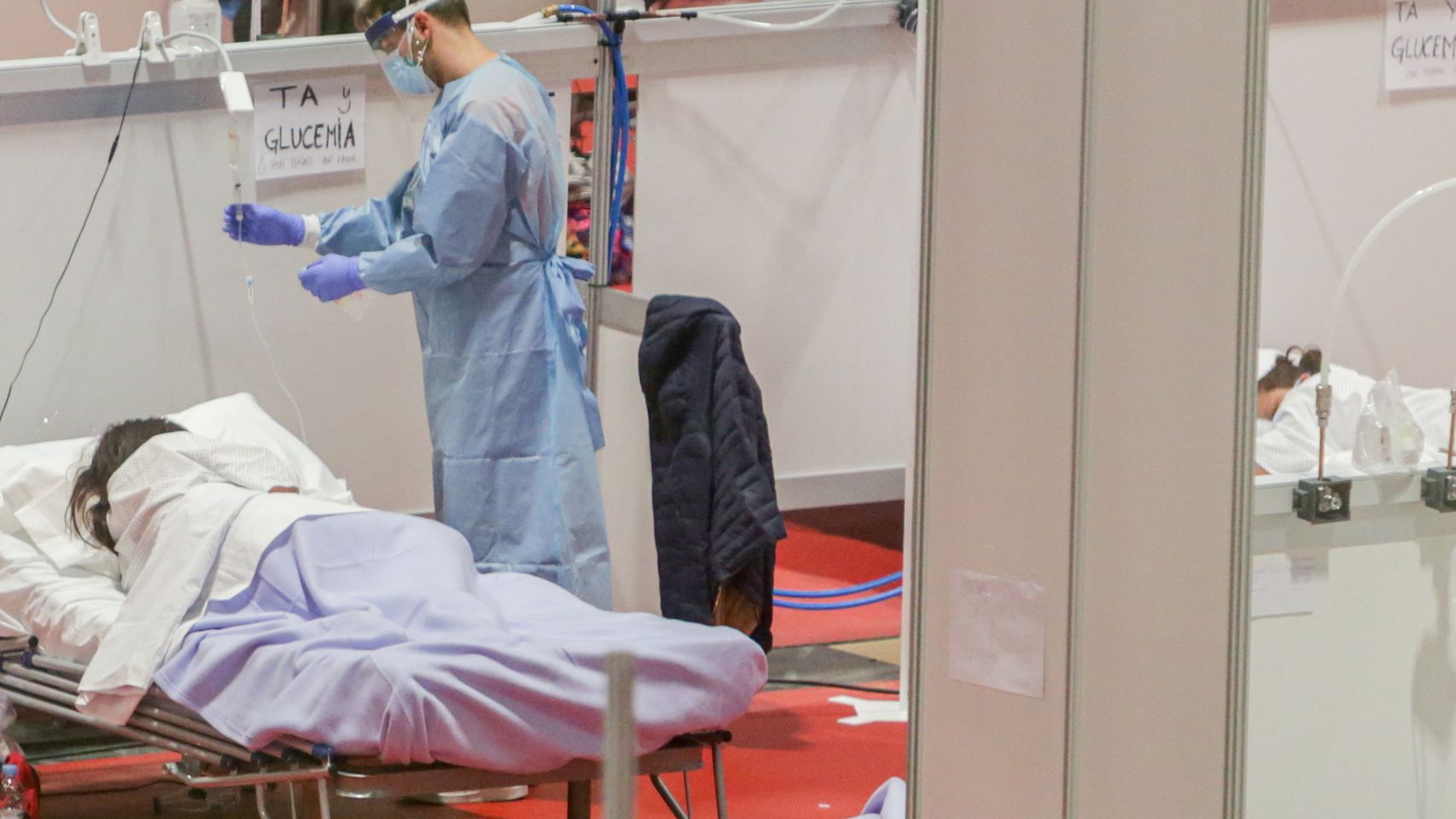 Un sanitario atiende a una paciente ingresada por coronavirus en el Hospital de Campaña montado en el recinto madrileño de IFEMA.