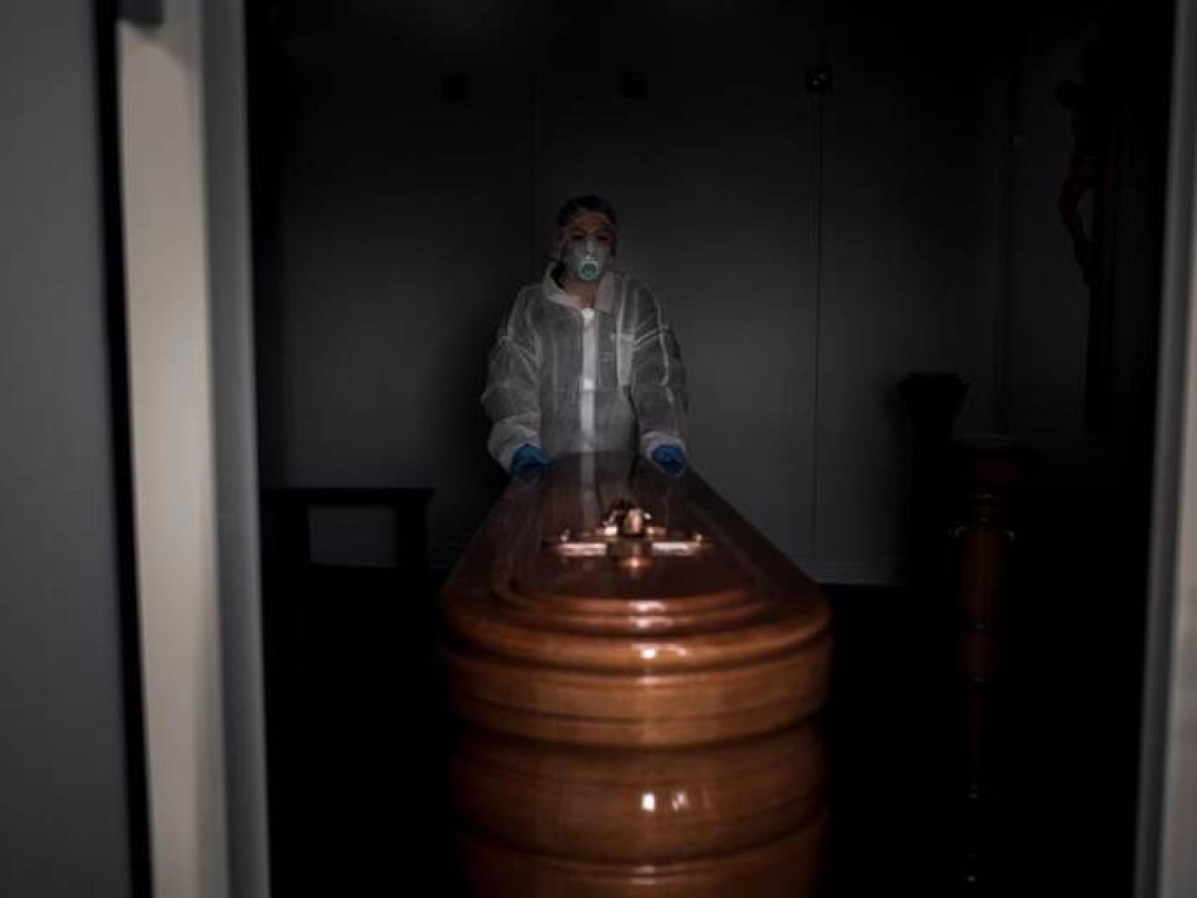 Una sanitaria traslada un ataúd.