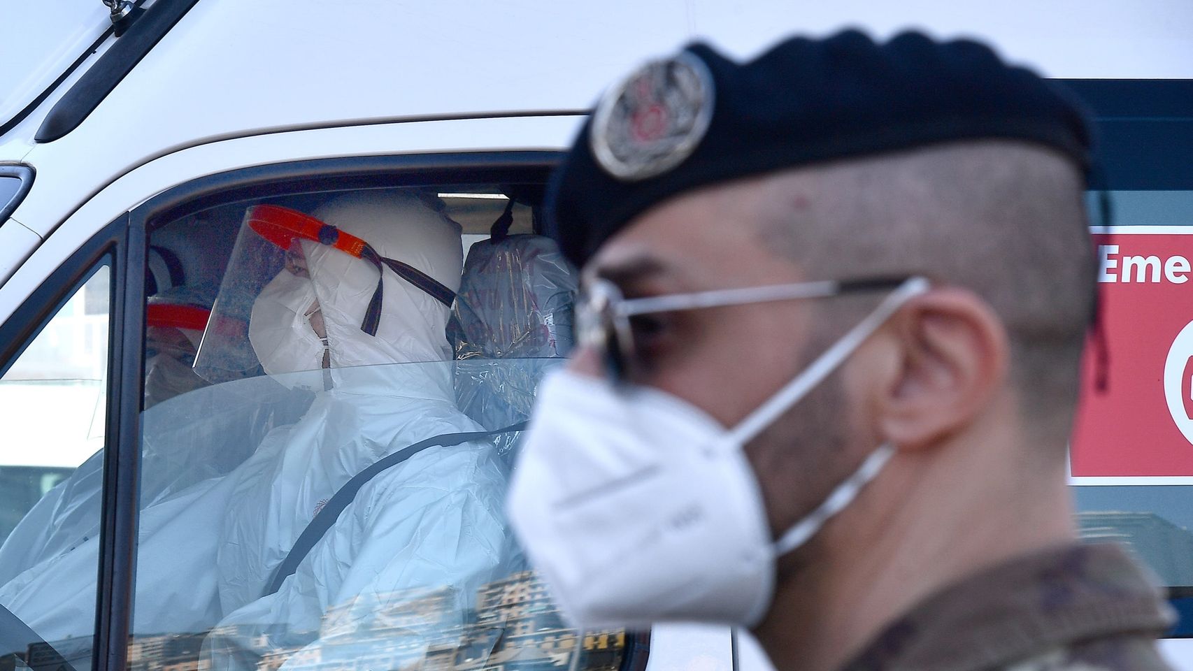 Un soldado frente a trabajadores sanitarios con mascarilla en Génova