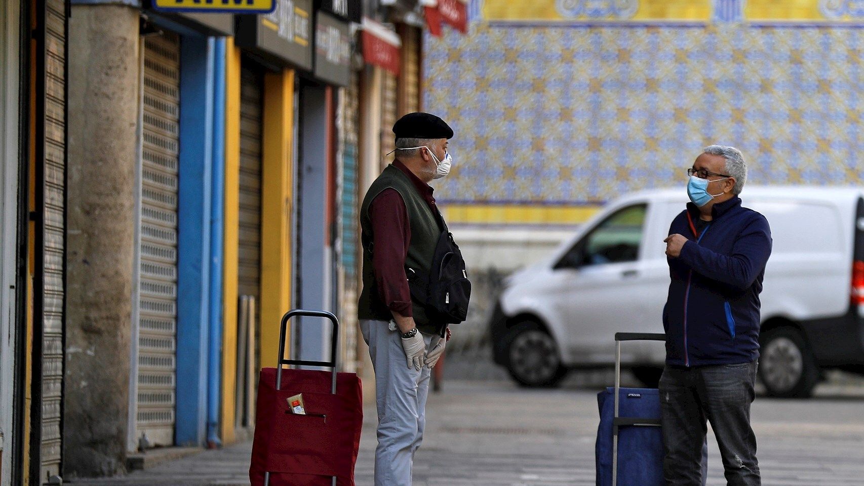Dos hombres conversan manteniendo las distancias a las puertas del Mercado Central de València. EFE/Manuel Bruque