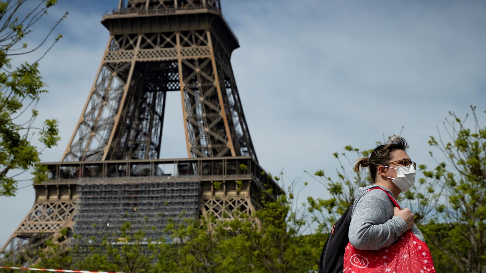 Una mujer camina con mascarilla cerca de la torre Eiffel