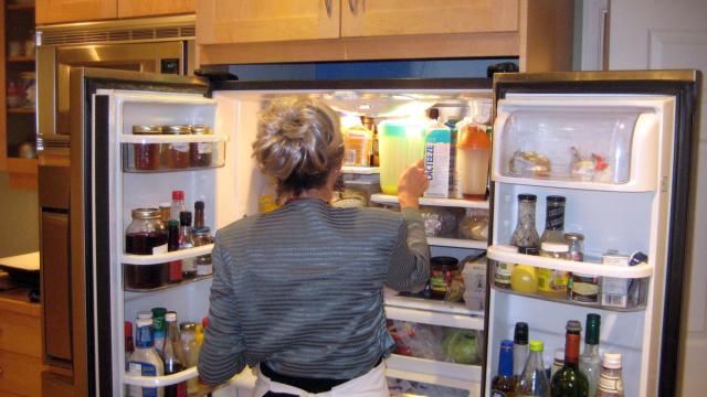 Una mujer mete alimentos en la nevera.