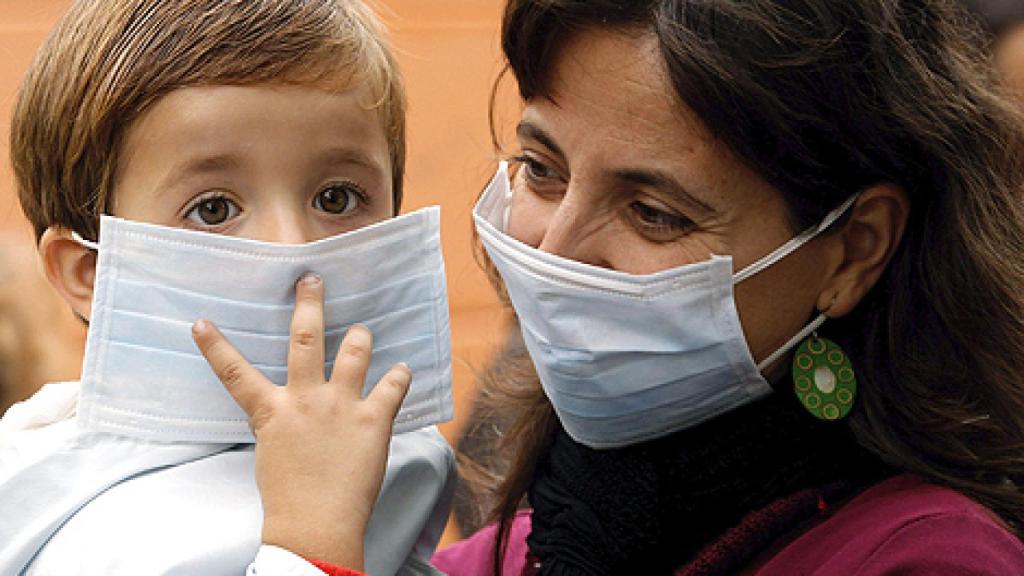 Un niño acude al coelgio con mascarilla, acompañado de su madre.