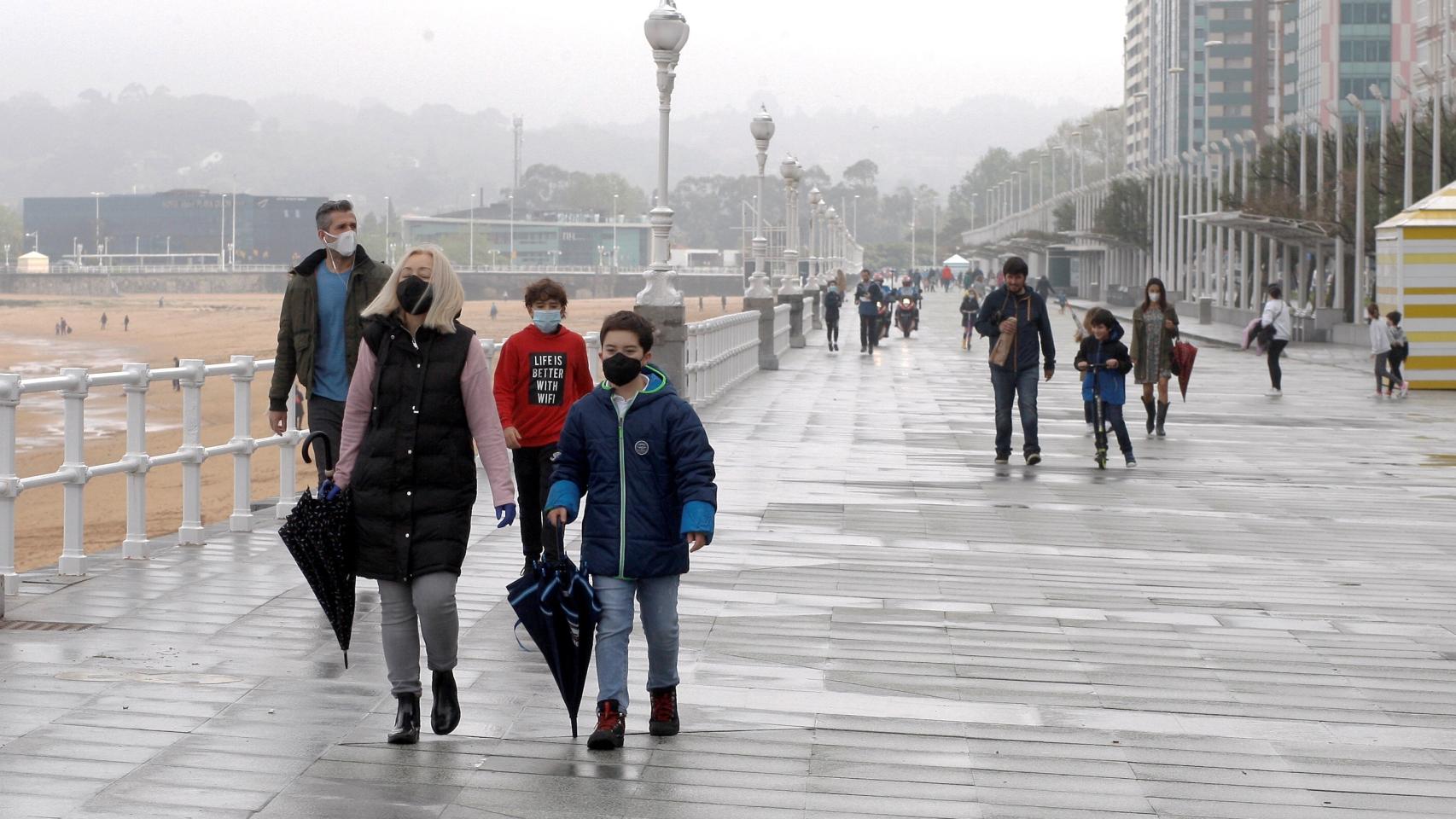 Familias pasean por el paseo marítimo de Gijón durante el estado de alarma.
