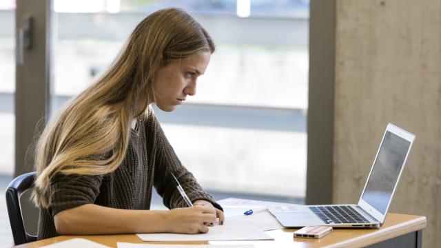 Una estudiante universitaria trabajando en casa.