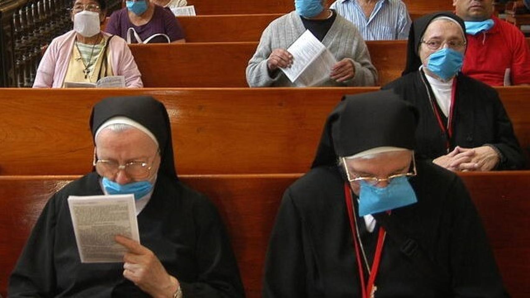 Monjas y feligreses asisten a una misa con mascarillas.